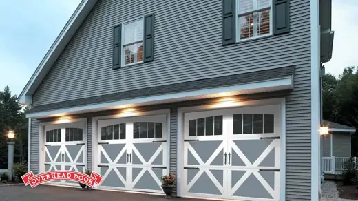 Three white garage doors are featured on a grey home.