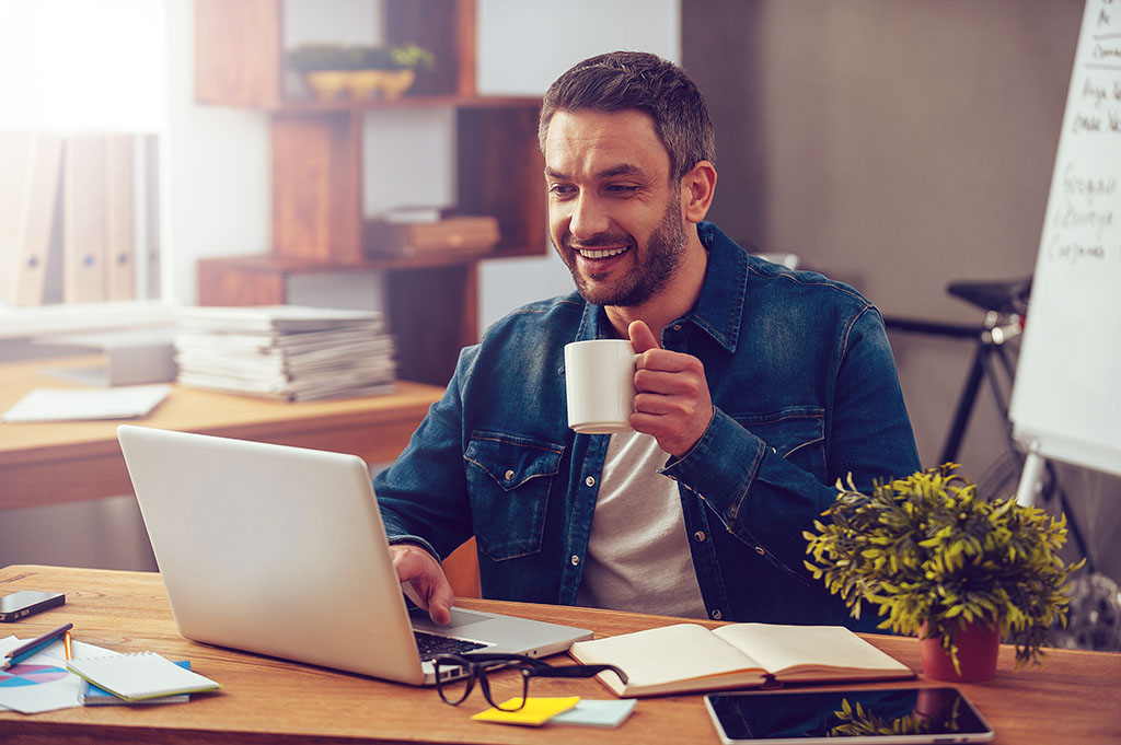 An office worker enjoys a cup of coffee in his garage transformed into a home office.